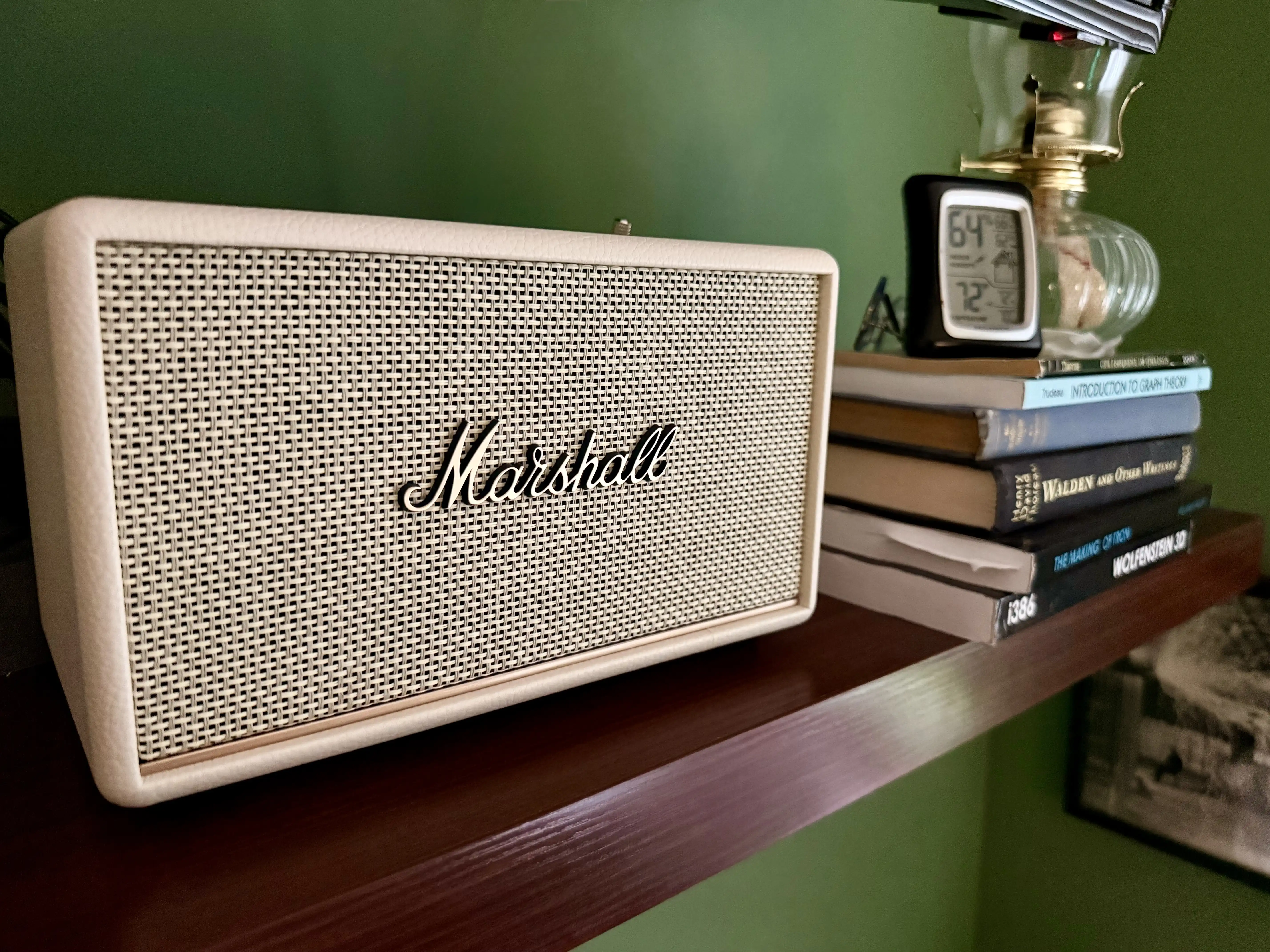 Cream Marshall speaker on a shelf next to a stack of books